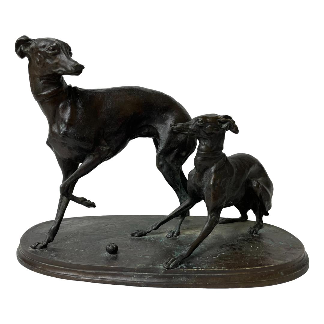 Main photo of the greyhound bronze signed Mene displayed longways with the small greyhound in the foreground and to the hind end of the adult. The adult has its front left leg raised as if stopped in mid walk and looking back at the juvenile who appears to be ready to pounce in play.