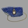 Main photo of gold pearl pendant &chain with the pendant hanging off a side of natural lapis lazuli rock and the chain laid across the top of the rock and extended out from the left and laid in a circular form around the stone. The gold setting for the pearl is on a circular design which has 2 short arms, one above one below like a piece of string laid with one circle loop and the end of the string laid above it. The ends of the gold 'string' acts as the bail for the chain - very neat!
