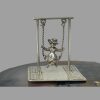 Main photo of miniature girl on swing seen from an eye level with the girl forward facing. The piece is displayed on top of a slice of natural agate. This is an articulated piece with the swing actually swingable! Lovely desk toy gift.