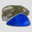 Main photo of Norwegian blue enamel brooch displayed leaning against a natural rock with gold flecks with the enamelled front on display. The shape of the brooch is like a set square ruler but not 90 degree angle! It also has a light concave design.