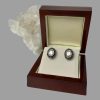 Main photo of rose cut diamond earrings displayed inside their box and forward facing. To the centre of each earring there is a large rose cut diamond with its own silver frame. The blue enamel area is visible followed by outer circle of 16 smaller diamonds. The centre diamond gives a stunning shine. The box is a mahogany like wood with a cream interior. There is a rock of natural quartz crystal protruding from the left of the open box.