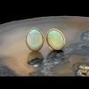 Main image of 18karat gold opal stud earrings displayed on top of slice of natural agate stone and shown with opal cabochons facing forward.