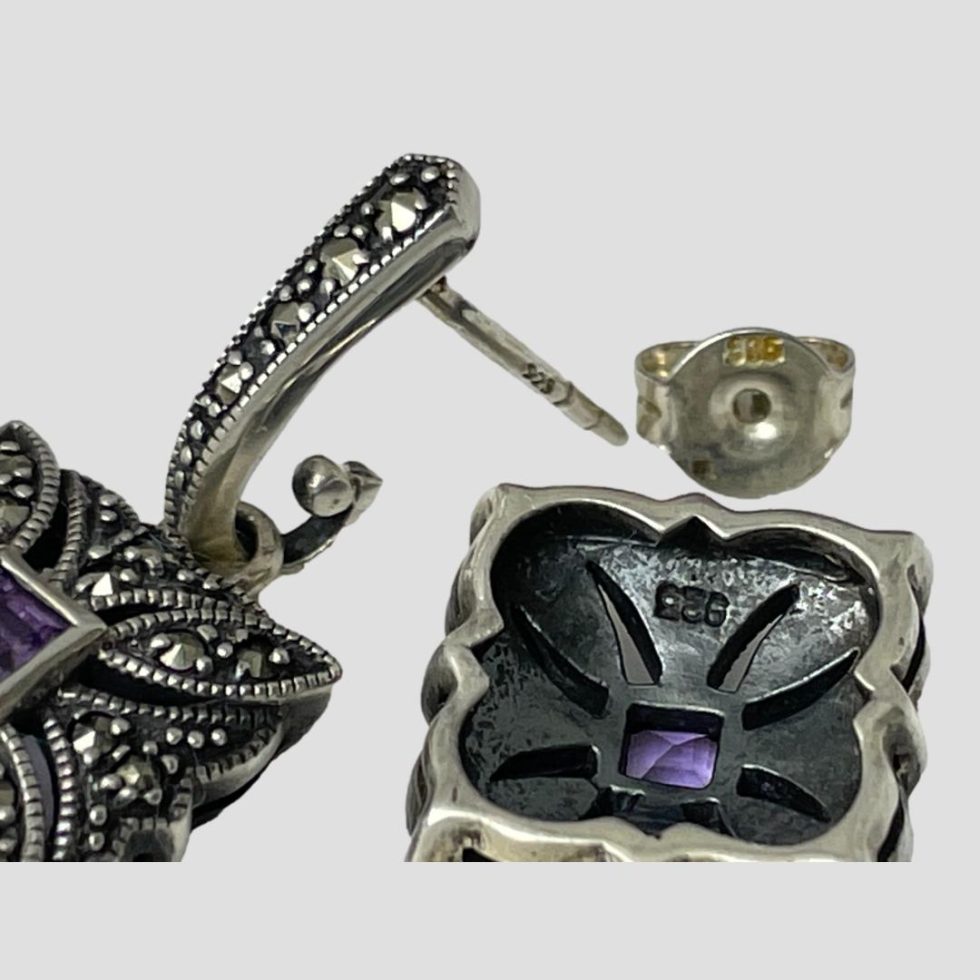 Close up photo of the silver hallmark (925) on the back of one earring square and one butterfly.