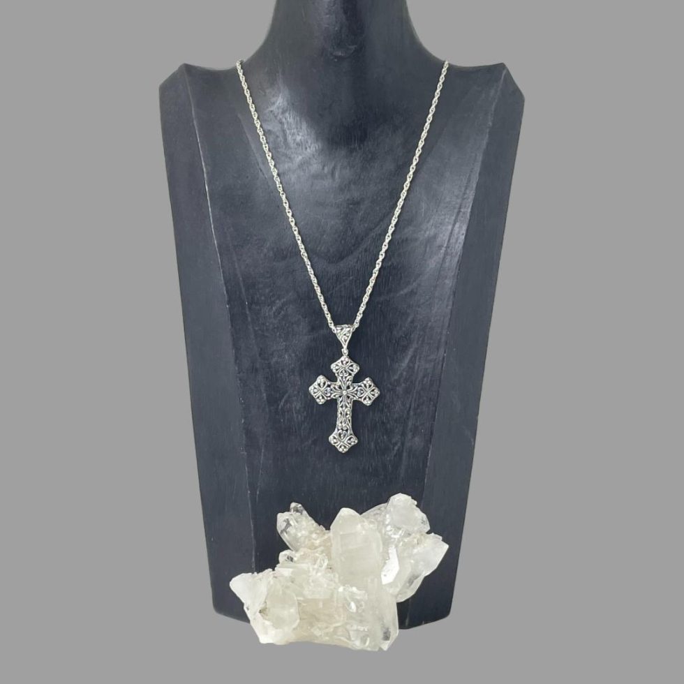 Photo of whole necklace shown displayed on a black wooden display stand. There is a rock of quartz crystal in the foreground.