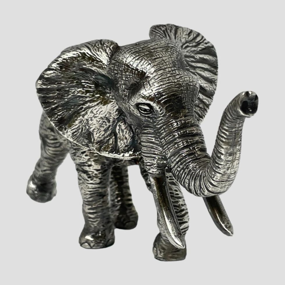 Close up of elephant taken from front. The head and raised trunk are facing bottom right.