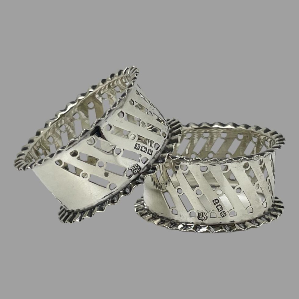 Both the sterling silver napkin rings are now displayed outside of their case with one balanced one side on top of other. The hallmarks are visible to both silver napkin rings.