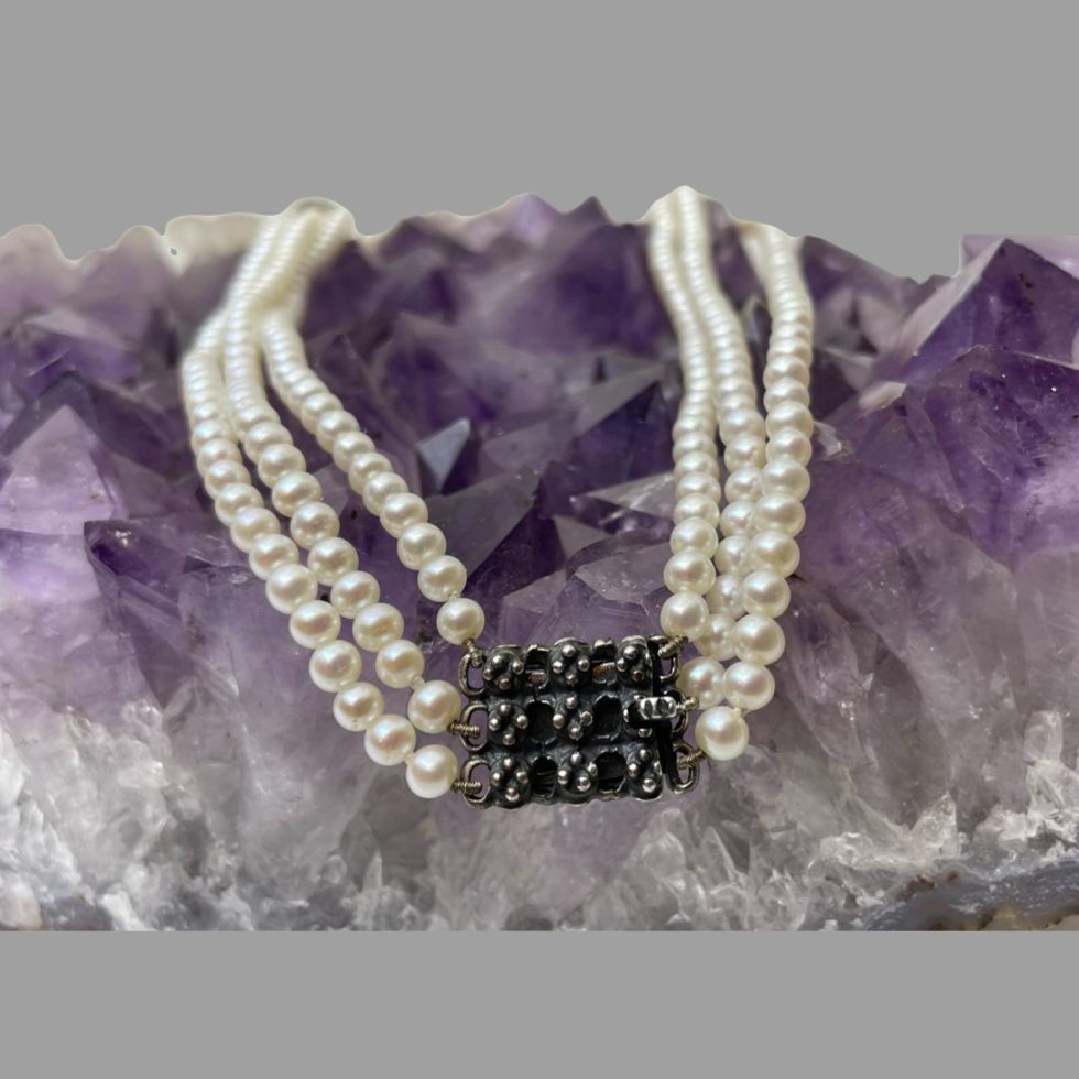 A close up of the closed clasp area of the pearl and garnet necklace.