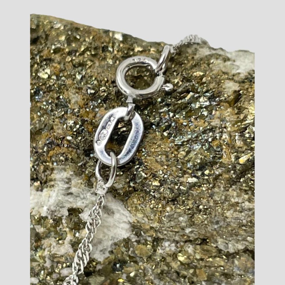 Close up photo of the hallmark on the clasp of the gold diamond cross and chain.