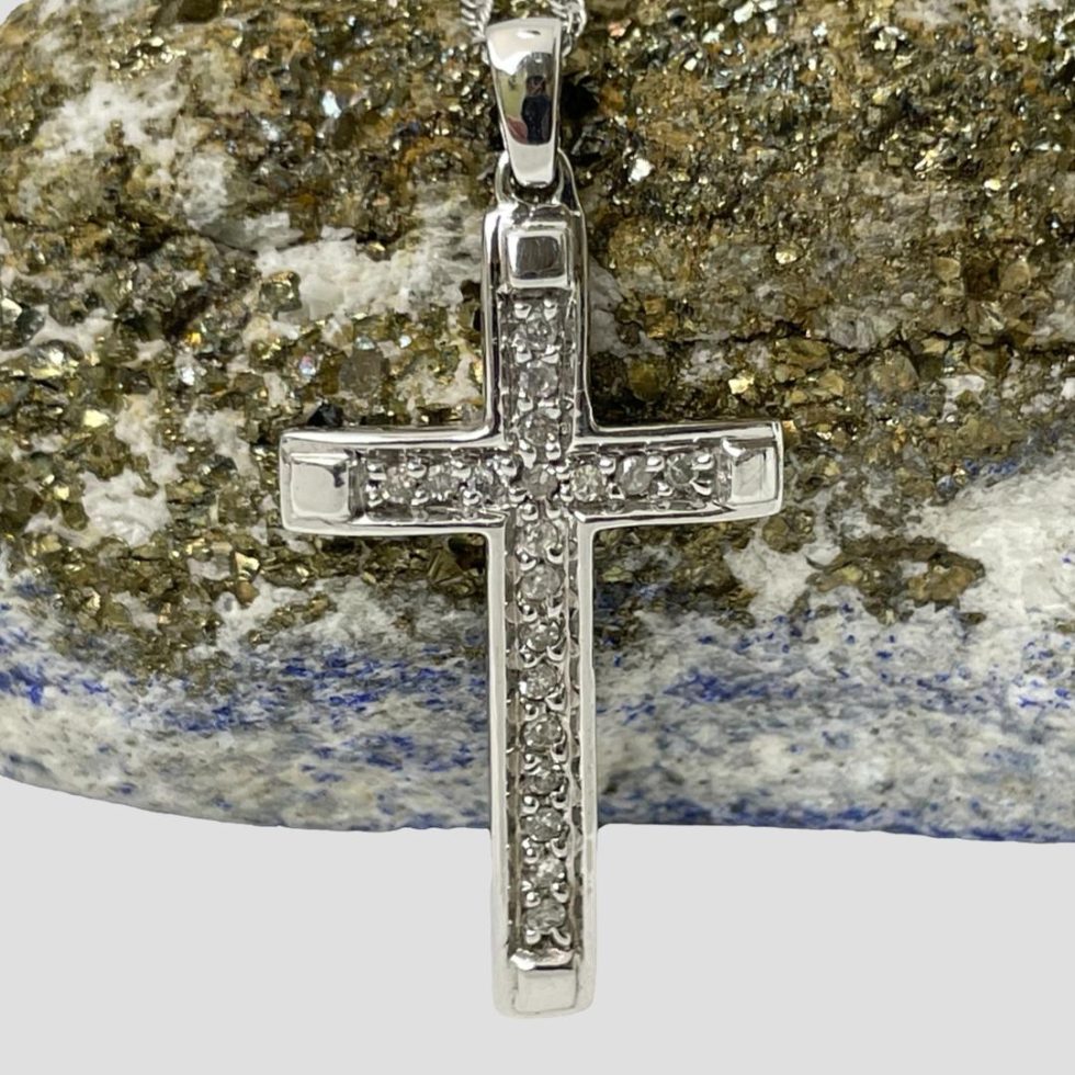 A close up photo of the gold diamond cross only which is shown leaning against a rock of lapis with gold ore