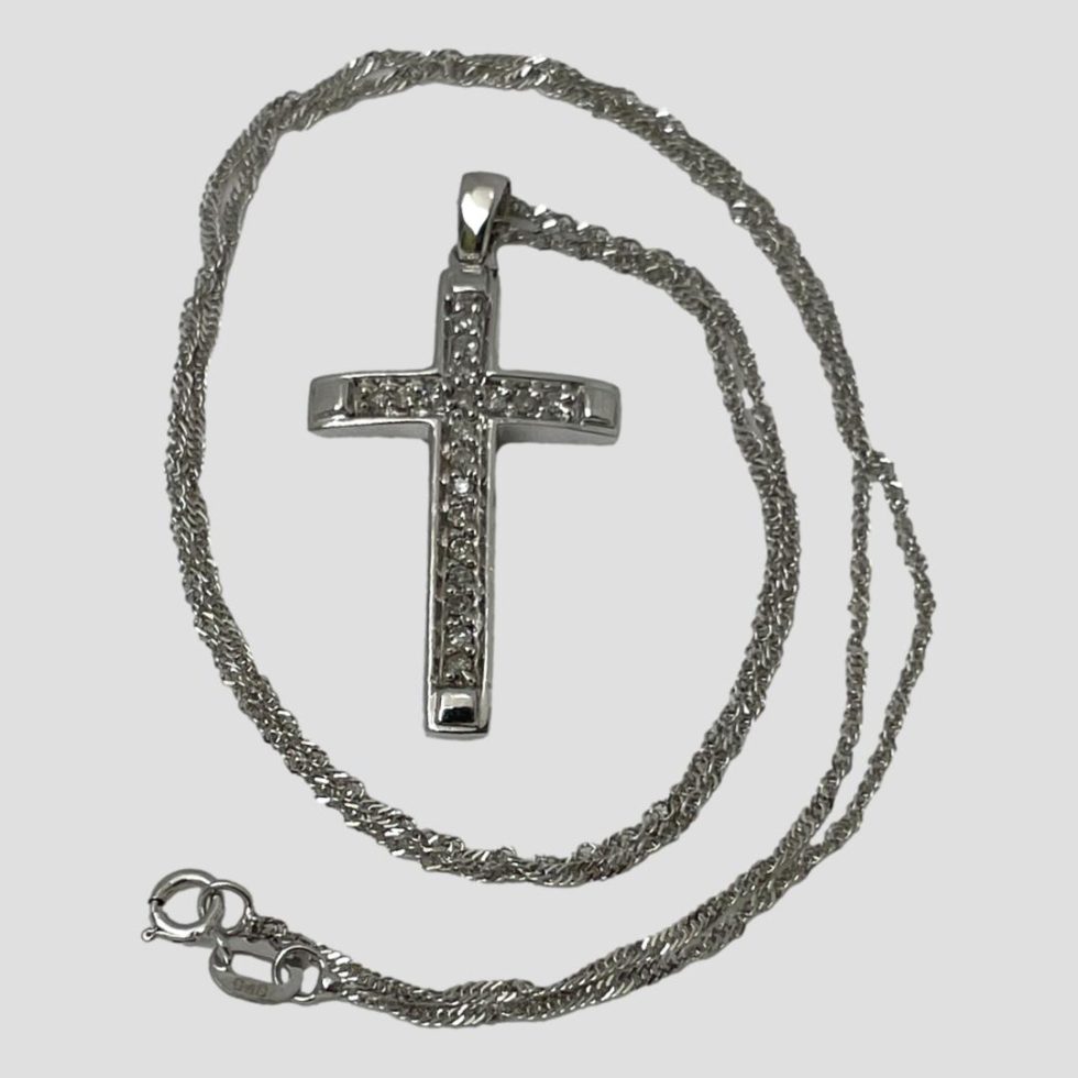 Photo of gold diamond cross and chain laid on a flat surface with the cross in the centre and chain coiled around it on the outside.