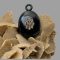 Main photo of Victorian jet locket seen displayed on top of a rock of desert sand rose and shown with monogrammed locket front forward facing.