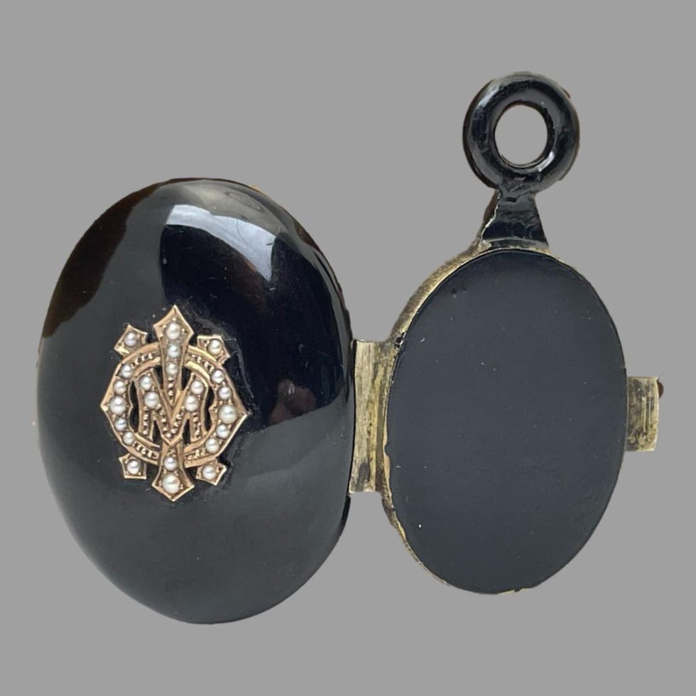 Photo showing the Victorian jet locket open with the exterior on display. Left side is the monogrammed front of locket with seed pearls and right is smaller back of locket which has the jet bail attached.