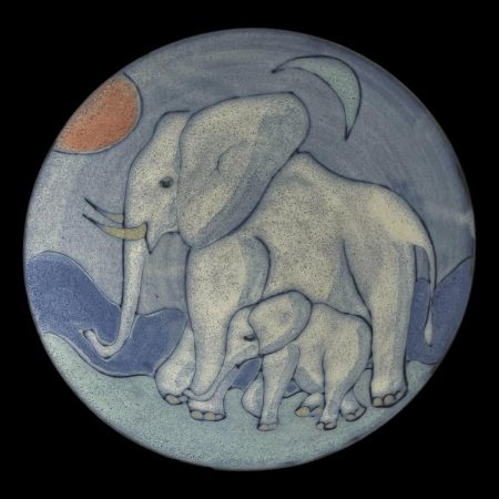 Main photo of Tessa Fuchs elephants bowl seen looking straight down into the bowl centre looking at the whole detail of the elephants adorning this piece of studio art. The sun is red and to the top left and crescent moon is blue and to the top right. The elephants are facing left towards the red sun. The elephants are a pale grey blue with blue areas to highlight the shadows. The adult elephant takes up quite a large portion of the picture. The calf walks beside the adult and fits between its front and back legs. The ground, mountain range in background and sky are different shades of blue - the darkest being the mountain range.
