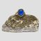 Main photo of the vintage 14 karat gold and blue spinel ring displayed on top of a small rock of natural lapis with the gold ore side on display. The blue of this spinel stone is stunning like a lagoon.