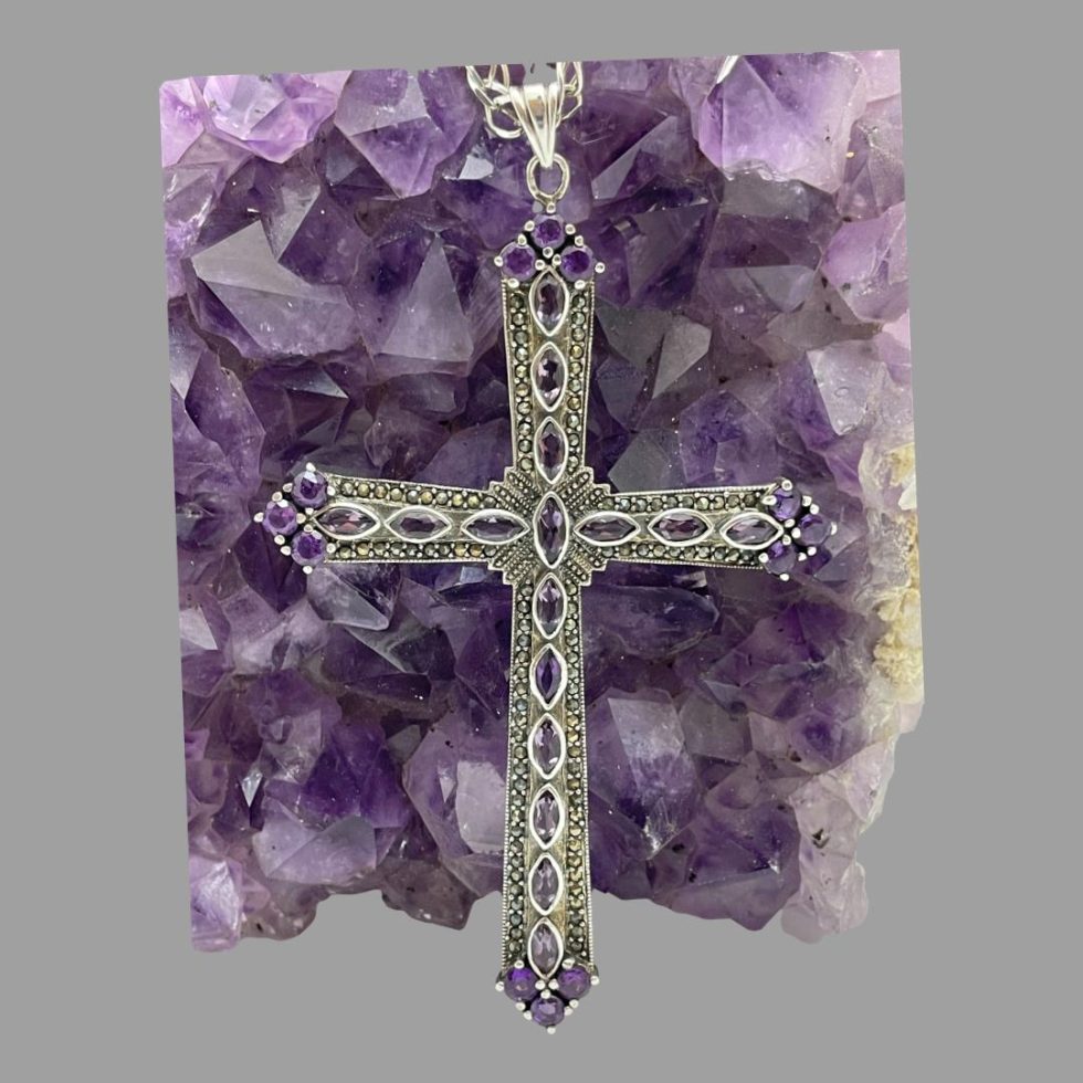 close up shot of the cross leaning upright against the amethyst crystal.
