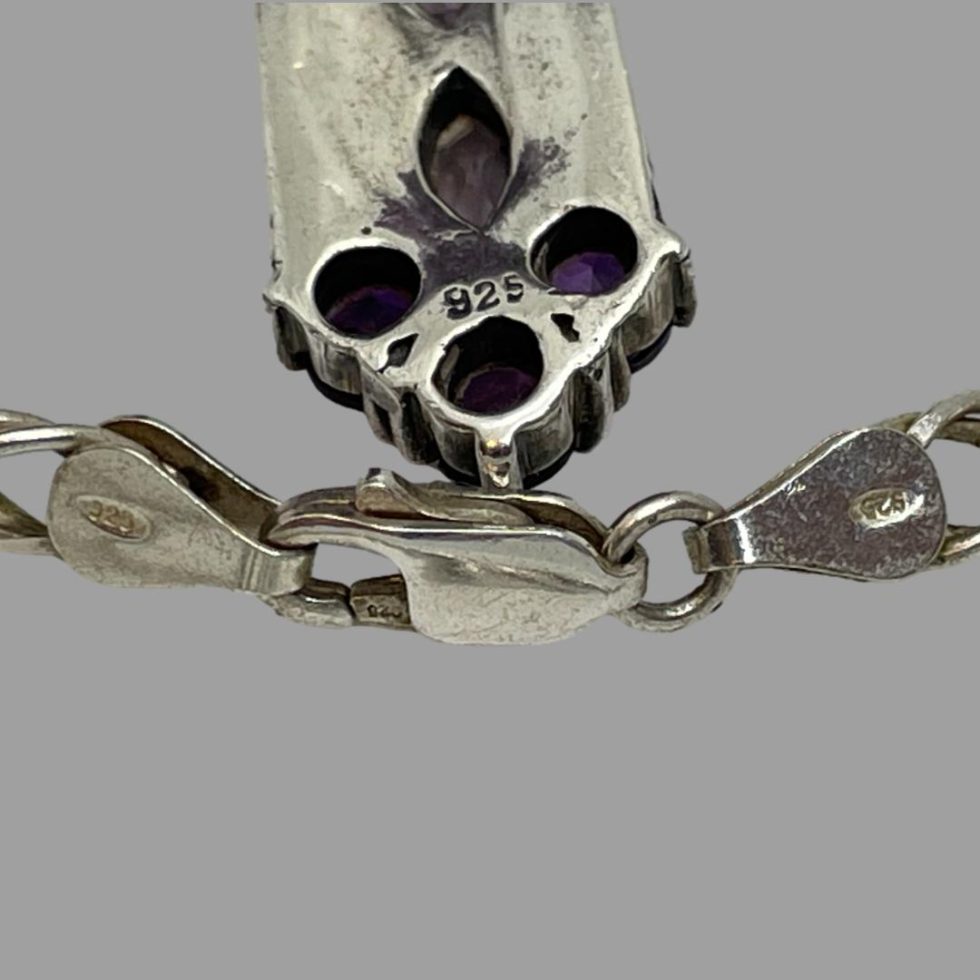 A close up photo of the 925 hallmark on the back of the cross and the chain clasp.