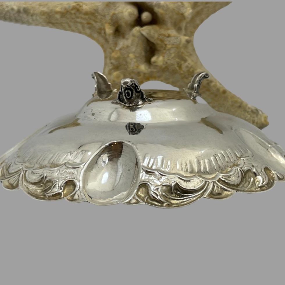 Photo of the mid-century Greek silver bowl shown upside down exposing the 3 feet and depth of the bowl. The 3 levels within the bowl is also evident from the outside. The starfish is again in the background.