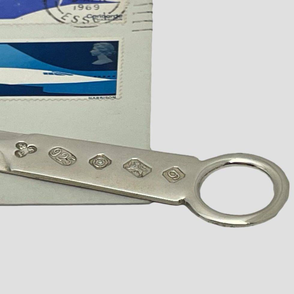 Close up of the full hallmark on the tip of handle of cased silver letter opener. Part of an old envelope and stamp is included in the photo.