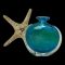 Main photo of unsigned Mdina glass vase see with one flat side facing forward. The clear glass ring around the bulbous area is visible with the beautiful blue and ochre glass sitting on top of that. There is a starfish displayed behind the vase to the left to give added seaside feel.
