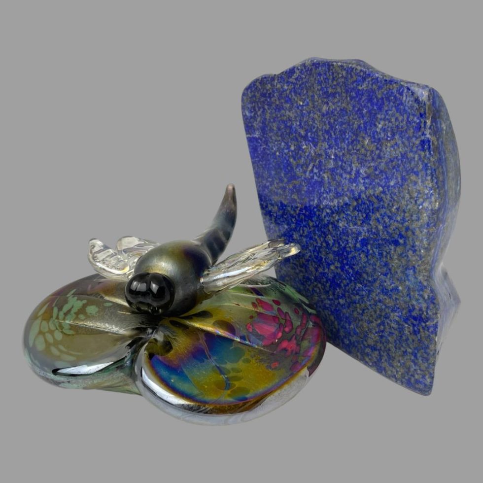 Main picture of ornament positioned left of a rock of lapis lazuli to evoke a sense of water. The lily pad is of multiple iridescent colours as is the body of the dragonfly making it somewhat camouflaged with clear glass wings.