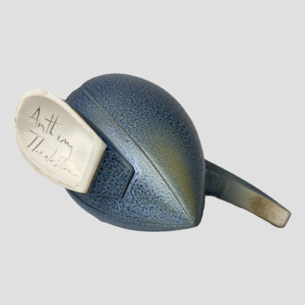 Photo of Anthony Theakston egret jug laid on its side to show the base. The artists signature is visible on the plain white base. There looks to be a slight discolouration of the underside of the handle but this is part of the glaze.