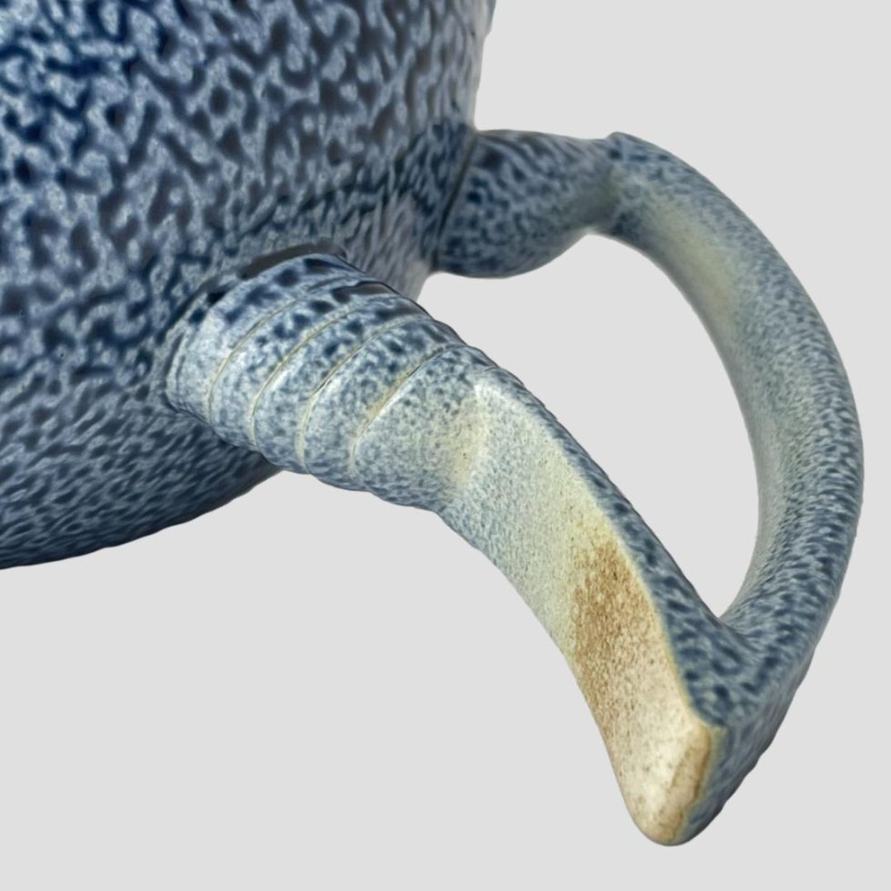 A close up photo of underneath the handle of Anthony Theakston egret jug showing the slightly yellow/orange colour on the tip. This is not wear or damage but part of the design.