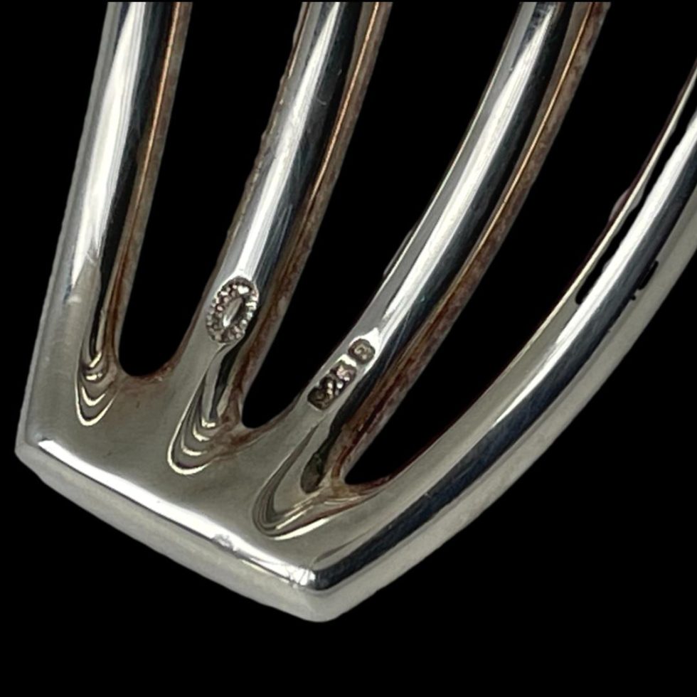 A close up photo of the hallmark on one end of Hans Hansen silver cuff.