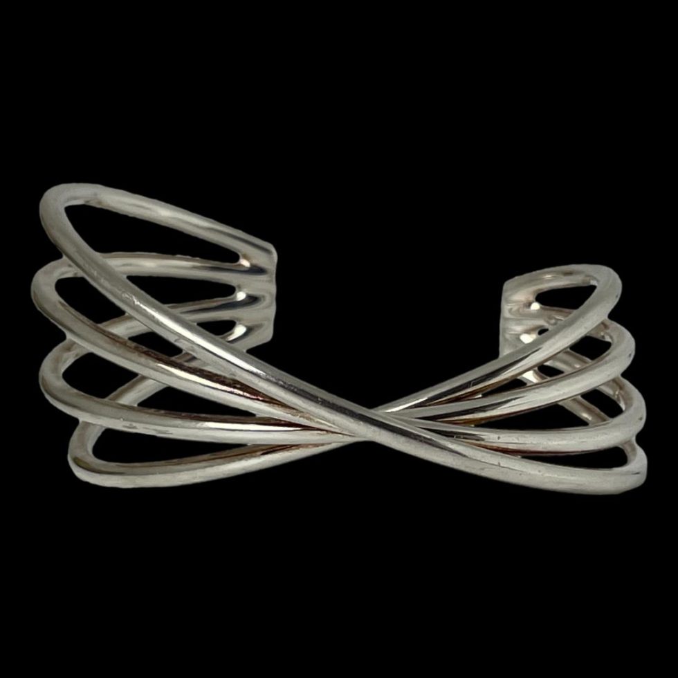 Photo of Hans Hansen silver cuff displayed on a flat surface with a black background and seen with the twist at the front of cuff in the foreground.