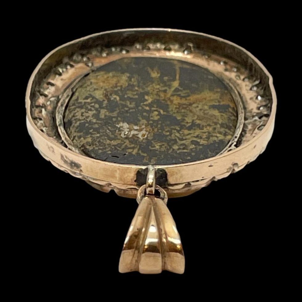 Photo of back of pendant seen with the bail in the centre foreground. The angle is looking diagonally down and shows the natural back of the stone.