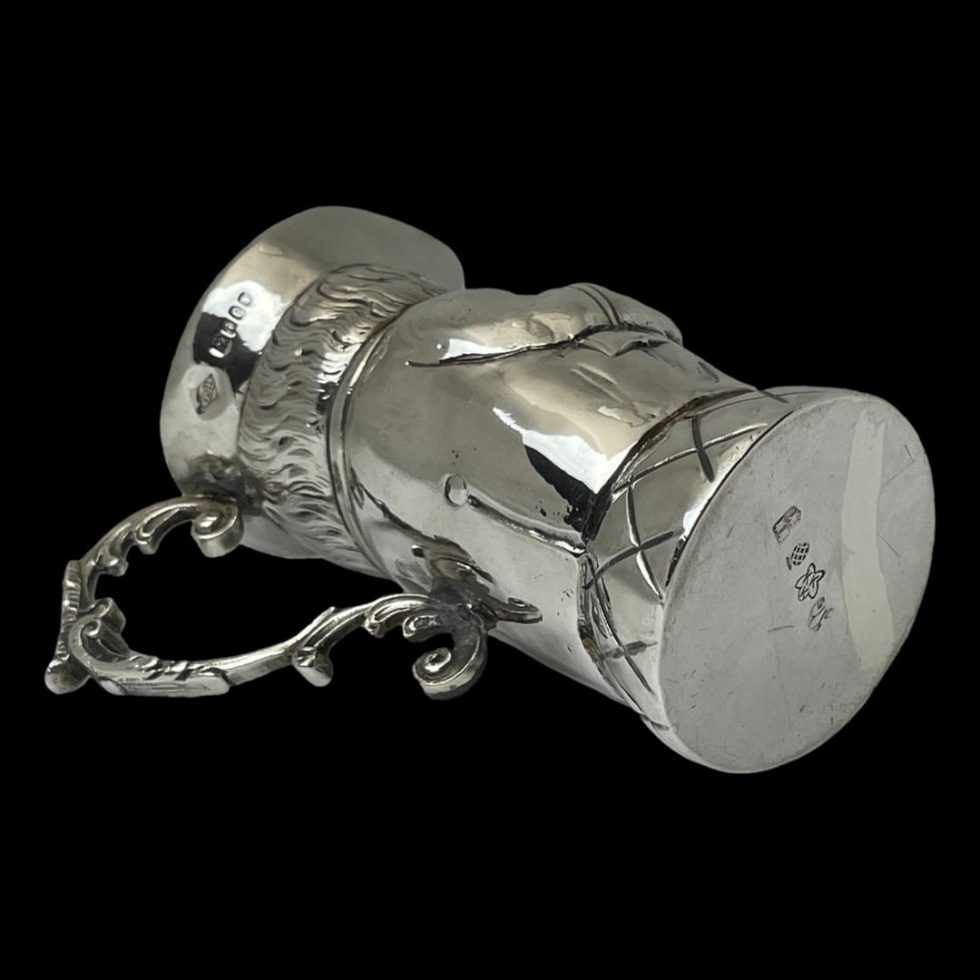 Photo of the jug laid on its side with the handle in the bottom left. Here we can see the German hallmark to the base and the London import assay office hallmark on the hat.