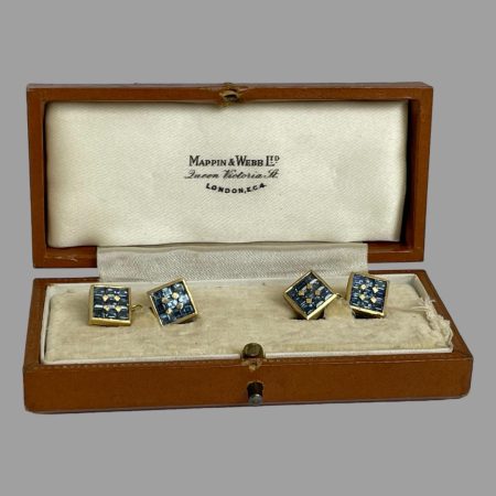 Main photo of 18kt gold sapphire cufflinks displayed inside the box which is included but not original. The sapphire ends of both ends of cufflinks are facing up and on display.