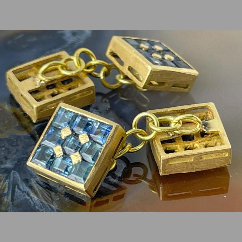 A close up of the 18kt gold sapphire cufflinks which are still displayed on top of some natural agate this time showing one sapphire side up and other face down.