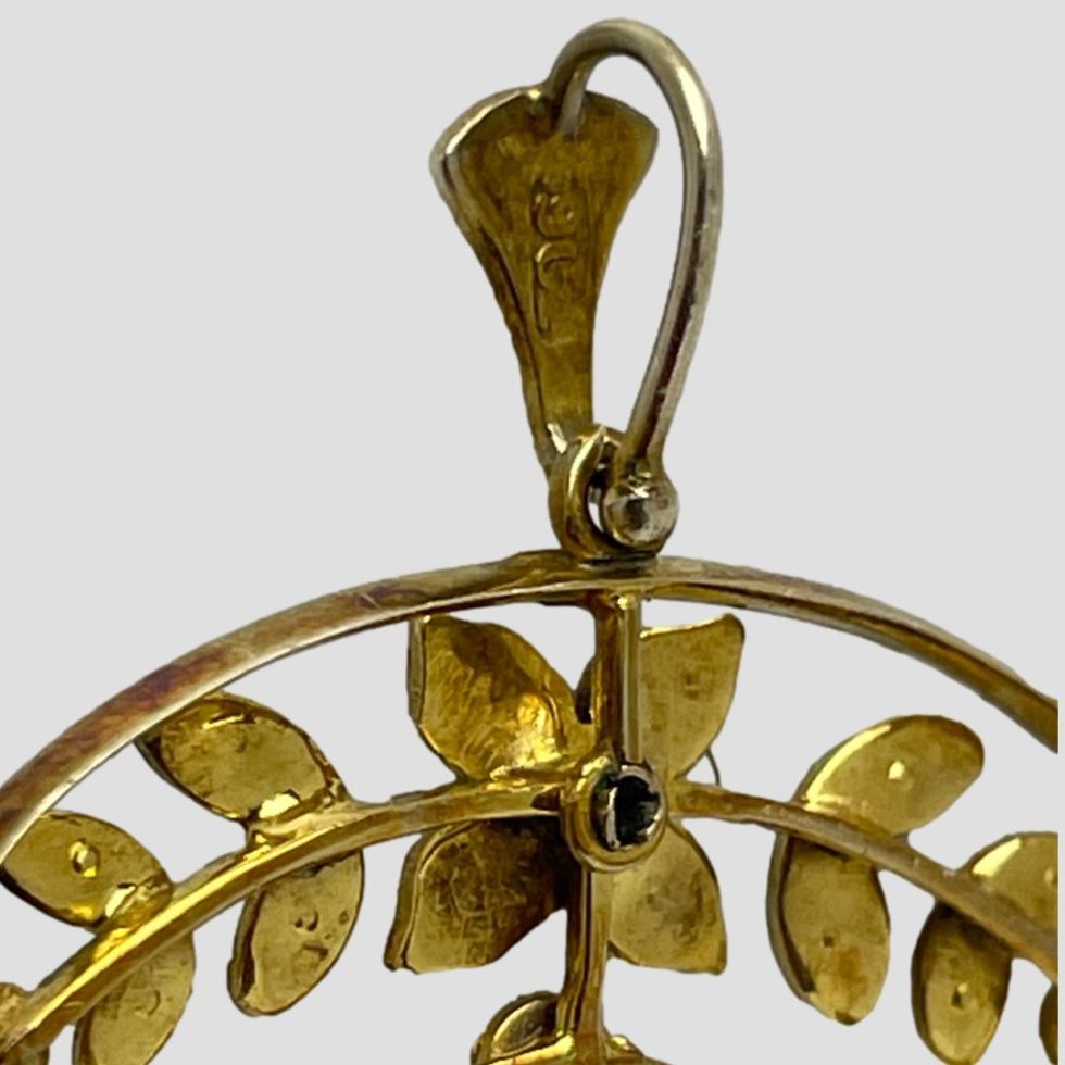 A close up photo of the 9ct hallmark at the back of the bail of Edwardian gold peridot pendant.