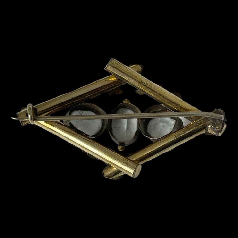 Photo of the back of Victorian Pinchbeck topaz brooch displayed on a plain black background. The pin is shown closed.