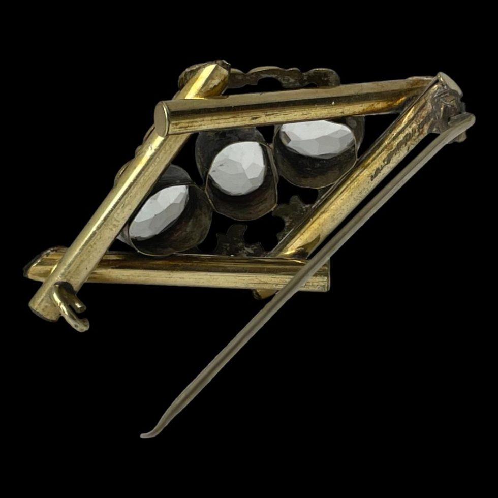 Photo of Victorian Pinchbeck topaz brooch seen from the back with the pin open. The pin is used to prop up the brooch.