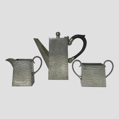 Main photo of Deco pewter coffee set shown with the 3 pieces in a row with jug to the left, coffee pot to centre and sugar bowl to right. Lovely uniform square design to each piece with pewter ear lobe handles to jug, sugar bowl and a bakelite one to coffee pot, Very aesthetically pleasing shape to each.