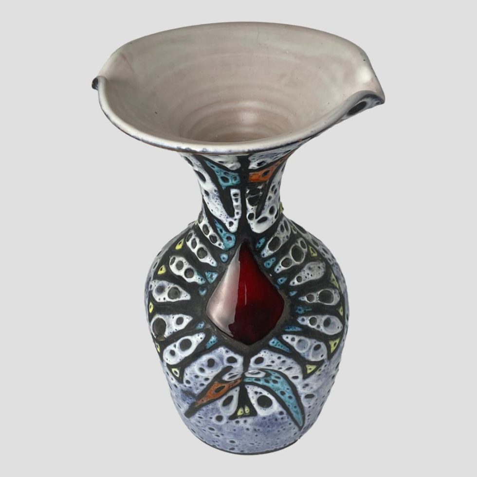 Photo of Vallauris fat lava vase seen with cherry red glaze area in the centre foreground. The angle of the shot is raised and looking diagonally down peering into the mouth of the vase.