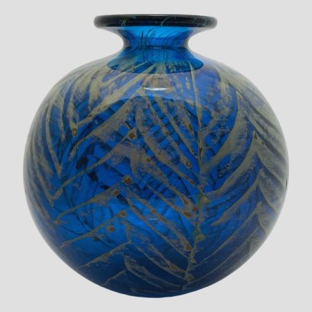 Main photo of signed Mdina ball vase seen from an eye level without light shining on it. The lagoon blue colour is stunning with or without light on it and the golden palm like fronds appear a darker shade.