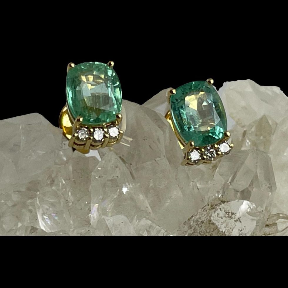 A closer shot of the gold emerald diamond stud earrings still displayed on a rock of crystal quartz with earring fronts forward facing.