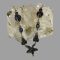 Main photo of sterling silver iolite necklace displayed laid across a rock of natural quartz crystal with just the front section housing the iolite stones on display. The central area of the necklace is a floral shape with 5 marquise cut iolite stones as petals. On either side of this flower is what could be a bee form-a round cut iolite with 2 vertically set marquise cut stones which could be wings. Next up is an oval cut stone followed by another bee like form. The iolite stones are slightly colour changing from a deep blue to a deep purple.