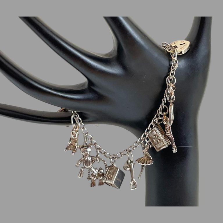 Main photo of sterling silver charm bracelet shown hanging on a hand display stand with the bracelet draped across the back of the hand showing some of the 15 charms.