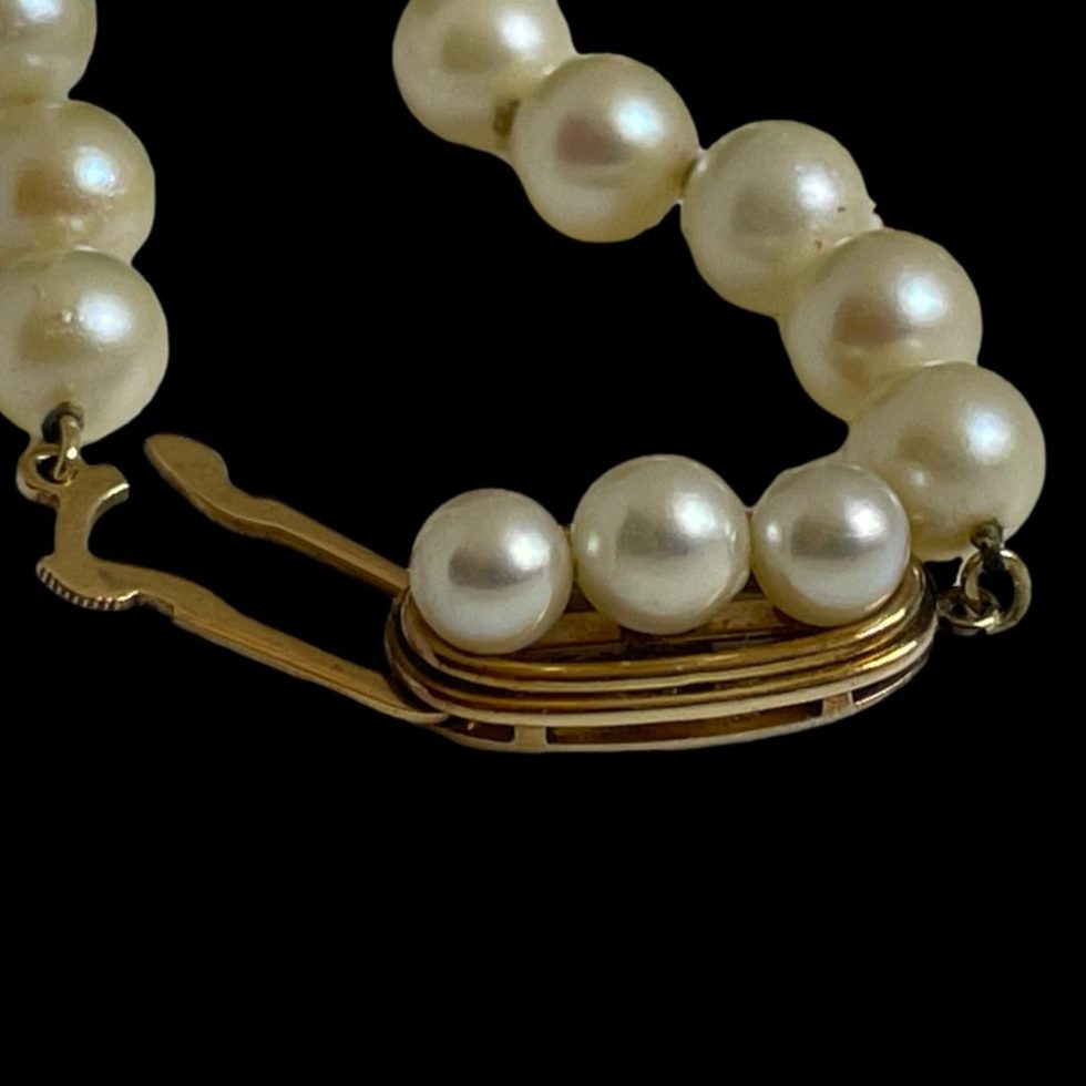 Close up photo of long cultured pearl necklace showing the clasp area with the thread hook undone but not completely out. (Needs unhooking to remove)
