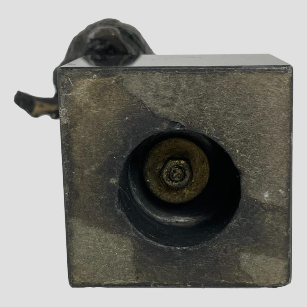 Photo of the base of the vintage small bronze owl The tip of the branch the owl is sat on is sticking out a fraction at top left side of base and the owls tail is visible to the top left.