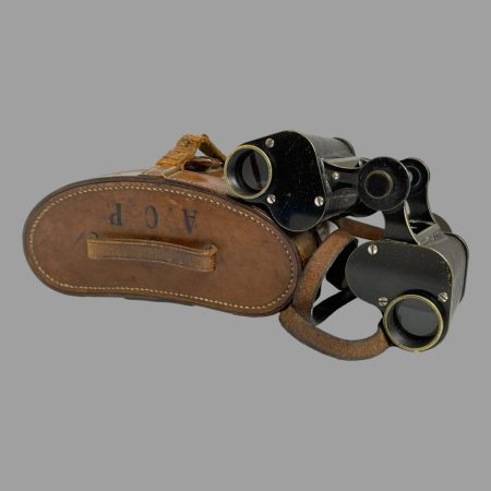 Main photo of Carl Zeiss Jena binoculars displayed astride its tan leather case which is laid flat with the top of lid on display. There are initials of A.C.P. at the top.