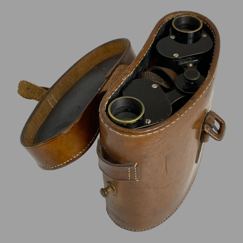 Photo looking down at Carl Zeiss Jena binoculars inside their case. The front of the case is facing towards bottom right corner with the lid fully open and to the top left corner.