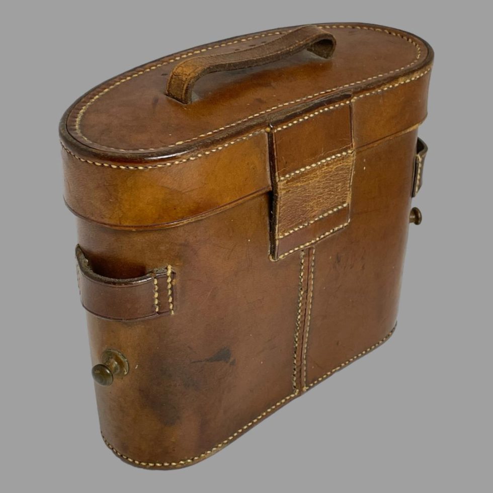 Photo of back of tan leather case of Carl Zeiss Jena binoculars. The back of the case is in good vintage condition. There are 2 strap buttons either side of case at bottom with leather loop above them. This is for a strap to carry the case which not included although maybe possible to use strap on the binoculars themselves.