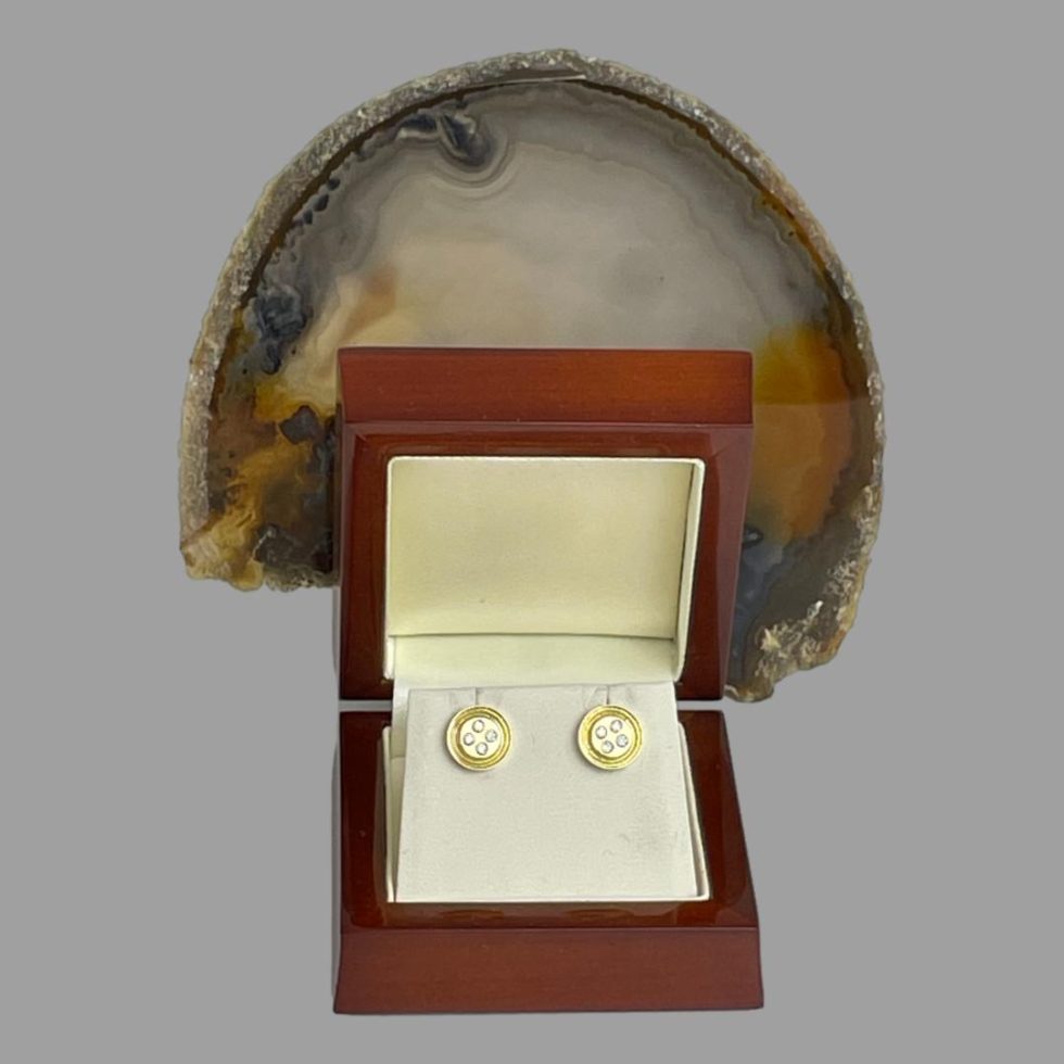 Photo of gold diamond 'button' earrings displayed inside their lacquered wood box and shown forward facing. A piece of natural agate is behind the open lid.