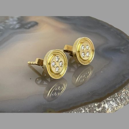 Main photo of gold diamond 'button' earrings displayed on top of a slice of natural agate and seen with the front of earrings facing towards the right. The 'button' detail is very clear - button like a shirt button; round with 4 thread holes. The diamonds making the thread holes have a lovely sparkle.