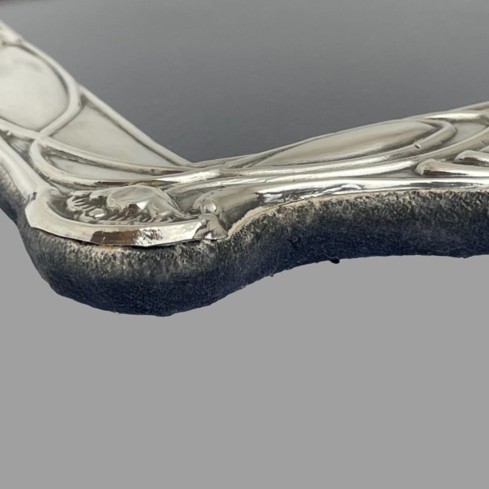 A close up photo of one top corner of the Nouveau silver photo frame showing the wear to the velvet.