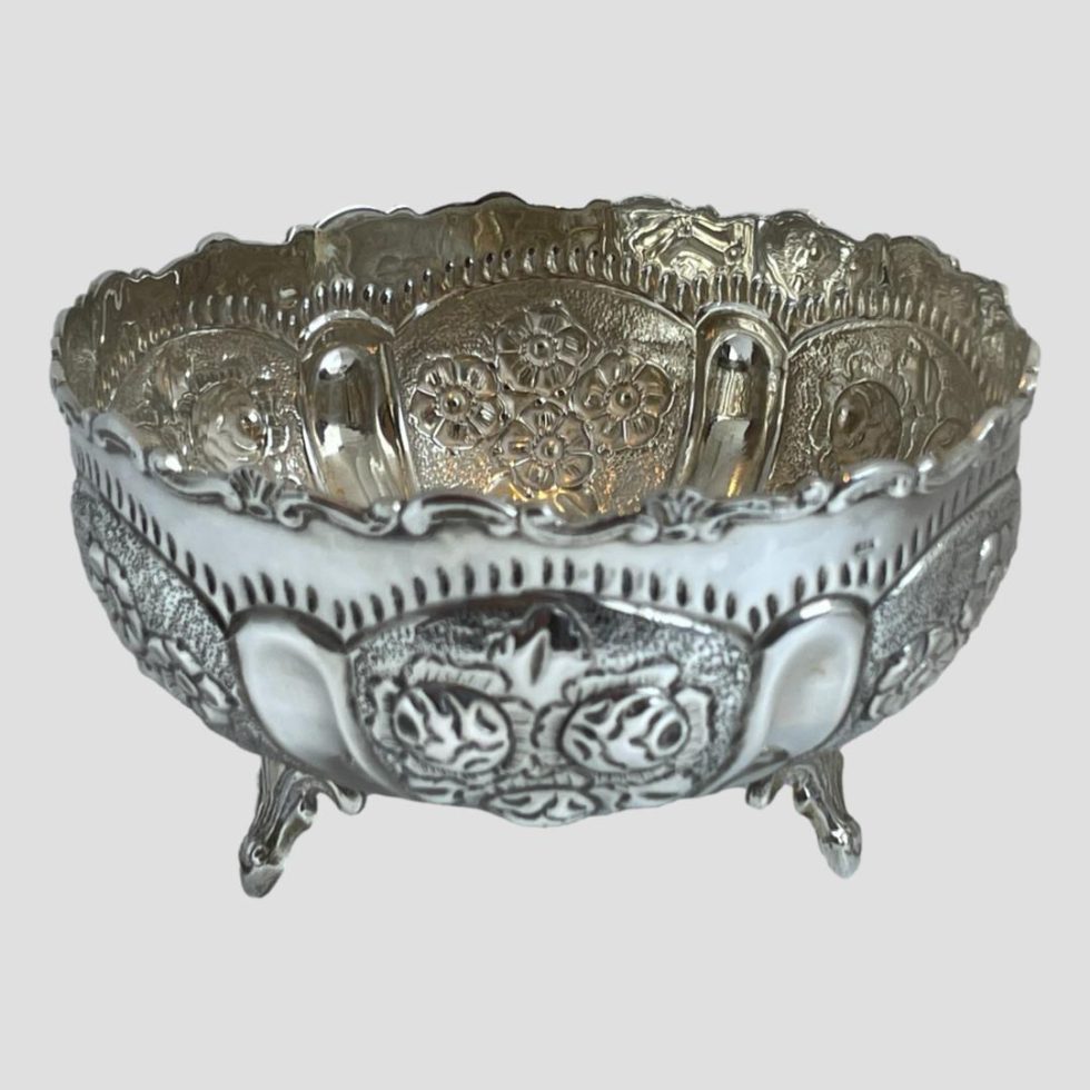 Photo of 835 Continental silver bowl showing the front panel with rosehips slightly out of focus and behind, the back of a panel with dog rose flowers.